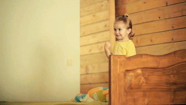 Happy jump. Cheerful child is jumping on bed in wooden house. Good childhood and physical development, joy and fun, success and celebration. Happiness for small stylish boy with long hair
