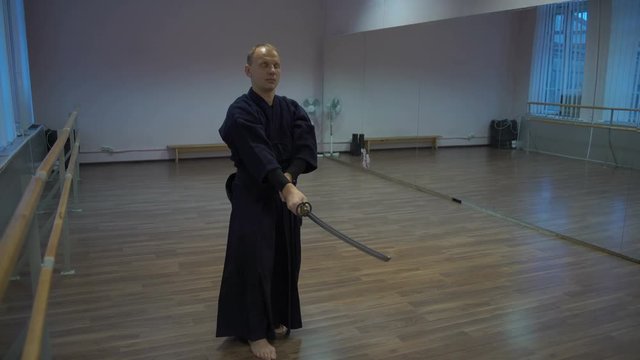 Master Kendo Performs the Kata Training with the Catana Sword in the Sports Hall with Mirrors