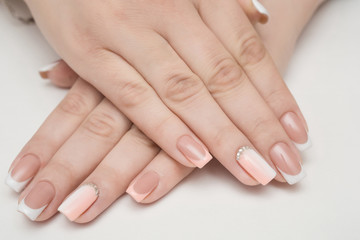 Hands with manicured nails covered with pink nail polish on fur background