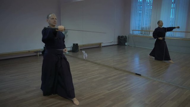 Master Kendoka Performs Kata in the Sports Hall with Mirrors, Makes the Fall with the Katan Sword