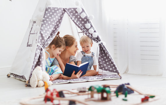 family mother reading to children book in tent at home
