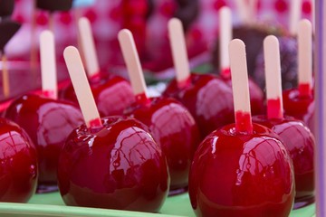 Sweet glazed red candy apples on sticks for sale on local market. Kids treat concept