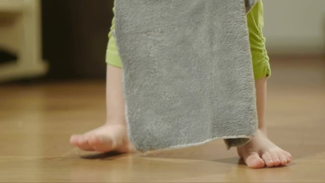 Close-up of a small child, 2 years old, trying to wash the floor in a room with a cloth napkin