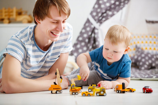 happy family father and son playing in toy car in playroom