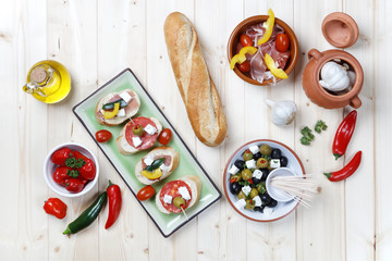 Variety of Tapas and Pintxos Snacks on light wood table shot from above