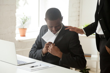 Satisfied black businessman hiding envelope into suit pocket receiving bribe from white corrupt...