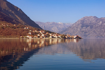 Mountains and small town of Prcanj are reflected in the Kotor Bay water on a sunny winter day. Montenegro