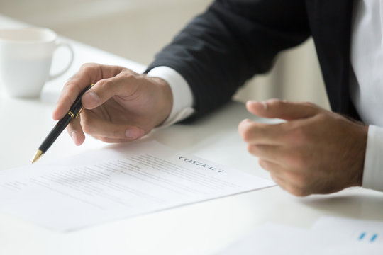 Businessman offering to sign business contract concept, promising good deal convincing to put signature, negotiating pointing on legal document terms, proposing partnership insurance, close up view