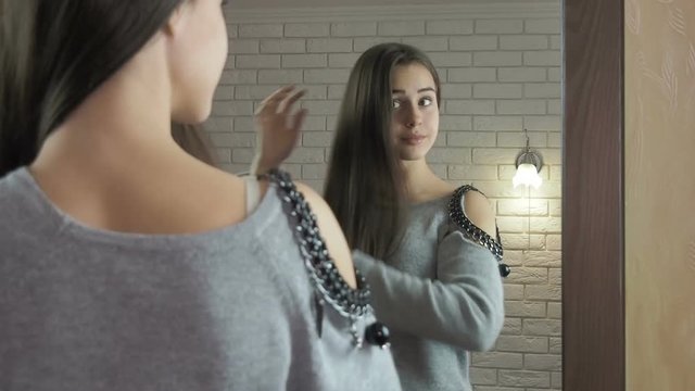 The girl in front of the mirror. A teenager girl combs her hair in front of a mirror.