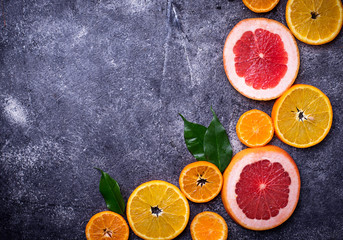 Different sliced citrus on dark concrete background