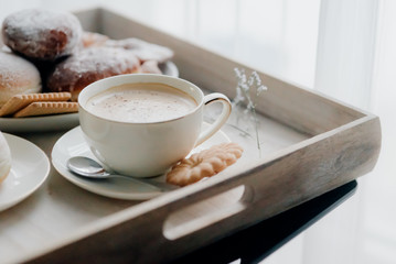 Donuts on plate on woode board with hot coffee for breakfast