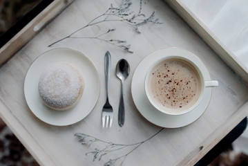 Donuts on plate on woode board with hot coffee for breakfast
