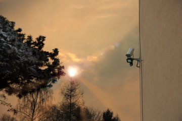 Kamera monitoringu na ścianie budynku, wschód słońca. - obrazy, fototapety, plakaty