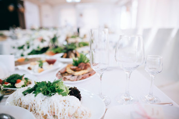 Wedding reception white table arrangement, floral centerpiece decoration, food. Catering service.