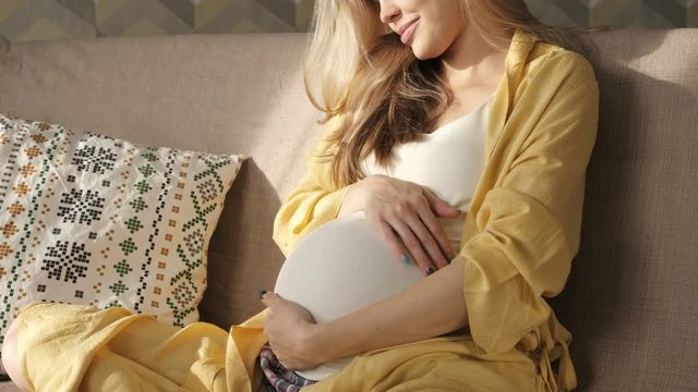 Beautiful pregnant woman caressing belly. Mom's hands on pregnant tummy. Expectant mother care. Happy young mom. Pregnancy and motherhood.