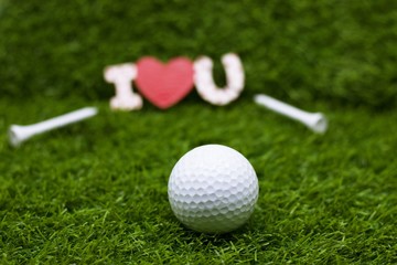 Red heart with golf ball on green grass meaning to golfer with love
