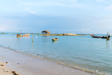 Asian idyllic coastal scene with traditional long tail fishing boats.