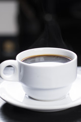 Hot black coffee in white mug, dark background