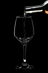 Glass of white wine is pouring wine from a bottle of white .