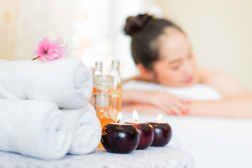 Obraz na płótnie Canvas Spa massage setting product with rolled, towel, compress balls ,Ingredients for cosmetics, body massage and thai spa.Blurred background is asian woman in spa shop.