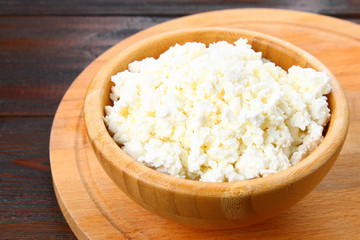 Home cottage cheese in a bowl on a wooden table.