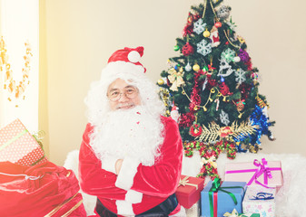 Senior Santa Claus with a bag of gifts surprising happiness in room with christmas tree for the New Year. Christmas, holidays, new year, currency concept