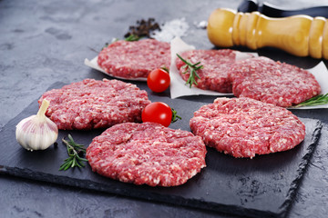 Fresh raw chopped meat for burgers on a dark slate.
