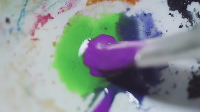 Wet brush mix blue green and purple color waterpaint on white plastic dirty palette, macro close up