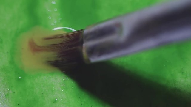 Paintbrush green watercolor smudges on wet paper canves, macro close up