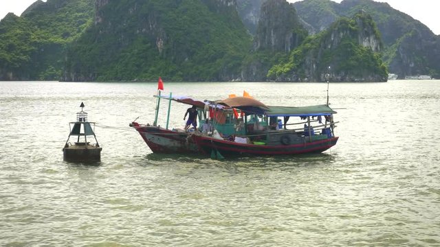 two fishing boats tied up to a buoy at halong bay, vietnam