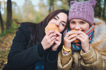 Two friends eating hamburgers at a picnic in the park.