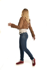 Fototapeta premium full length portrait of girl wearing brown leather jacket and jeans. standing pose facing away from the camera.