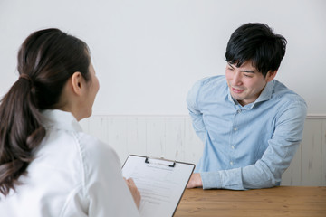 腰痛の男性とカウンセリングする女性
