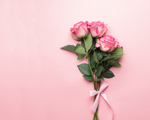 Bouquet of fresh roses with a pink ribbon on a pink background. View from above. Copy space. Card.