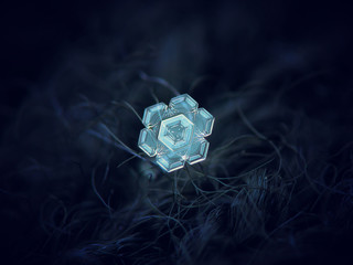Real snowflake glowing on dark textured background. Macro photo of real snow crystal: small star...