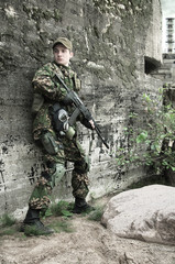 soldier with a rifle hiding behind an old concrete wall strengthening