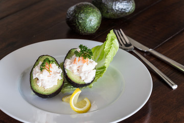 Shrimp salad in avocado on white plate.