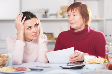 Upset mature woman and daughter with papers