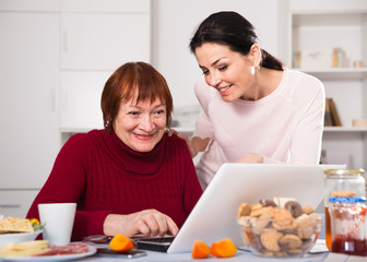 Mature women sitting and using laptop with  daughter