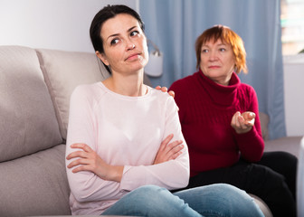 Sad mature female and daughter at sofa after quarrel