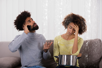 Woman Using Utensil For Collecting Water Leaking From Ceiling