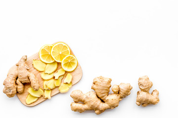 Fresh ginger root and lemon slices pattern on cutting board on white background top view copy space