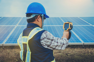 electrician working on maintenance equipment at industry solar power; engineer use IR camera to...