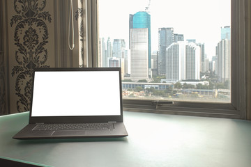 Blank laptop screen at home office with city skyline.  Nomad world travellor freelance for blogger and IT expert, web design.