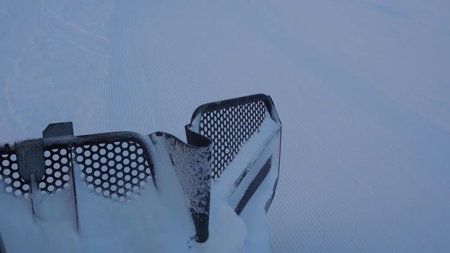 Footage of a snow groomer master blade as it climbs the mountain