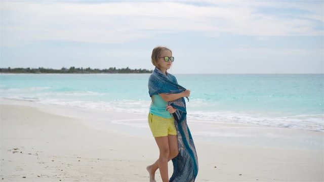 Little girl have a lot of fun on the beach. Kid enjoy beach vacation with pareo