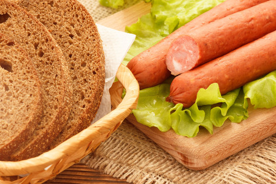 Smoked sausages with dark bread on lettuce salad