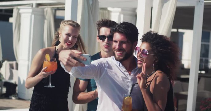 Young friends in sunglasses taking selfies use phone laughing feel happy on the party party beach couple summer man technology sun group beautiful outdoors friendship photo together vacation fun