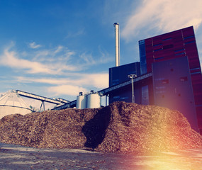 bio power plant with storage of wooden fuel against blue sky