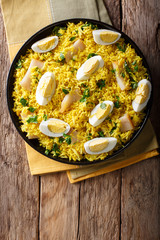 Tasty homemade Kedgeree with fish, boiled eggs, cilantro close-up on a plate. Vertical top view
